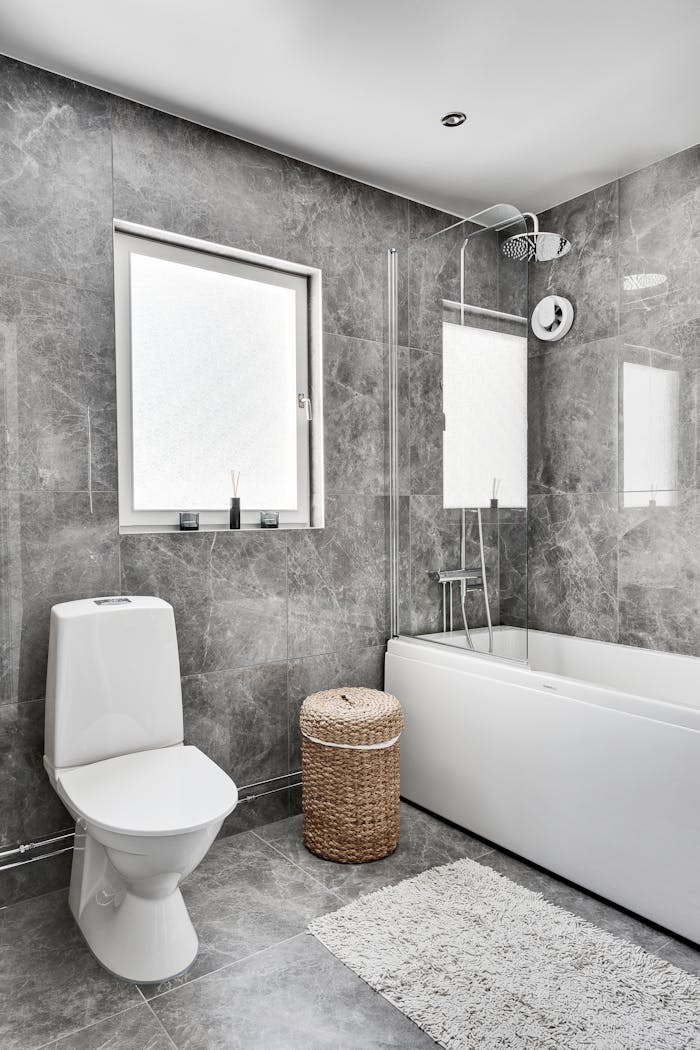 Elegant bathroom interior featuring marble tiles, toilet, and bathtub in modern design.