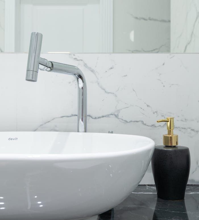Stylish bathroom featuring a modern chrome faucet, marble backsplash, and a white ceramic washbasin.